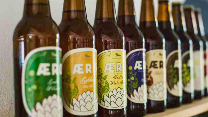 Ni brune ølflasker på række med forskellige mærkater fra Ærø Bryggeri.