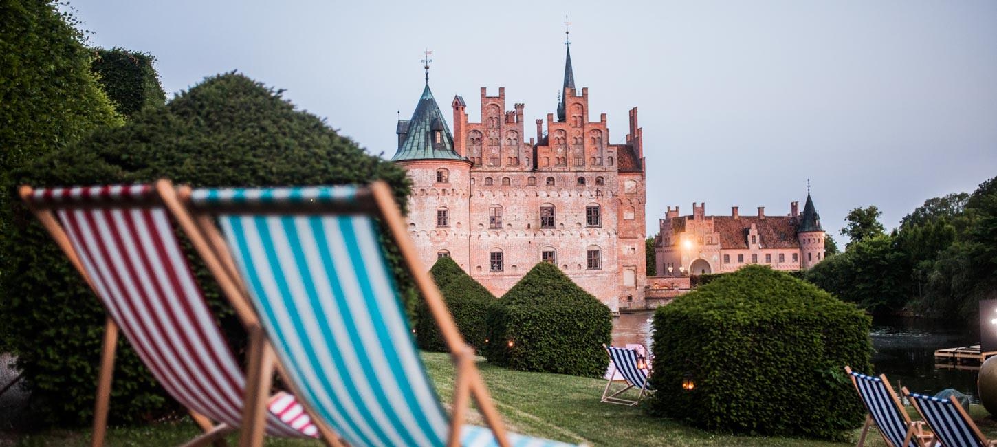 To af de klassiske stribede strand-liggestole i forgrunden - Egeskov Slot i baggrunden.