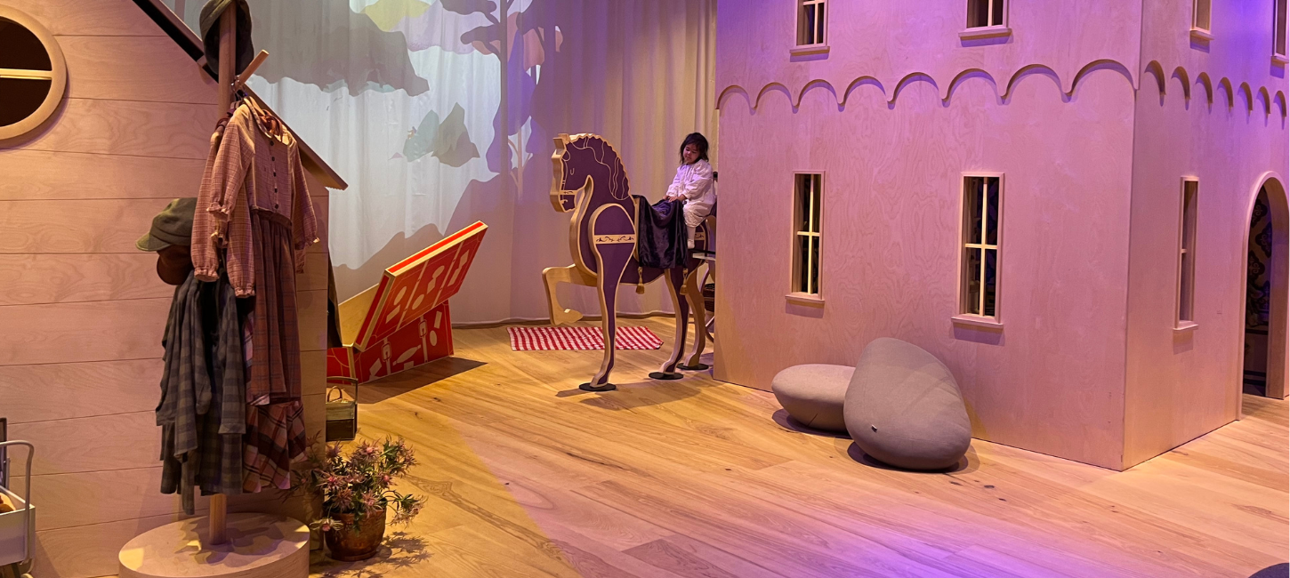 En lille pige sidder på en legetøjshest i Ville Vau, et børneunivers i H. C. Andersens hus i Odense. 