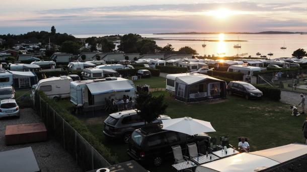 Solnedgang over havet og en fyldt campingplads.