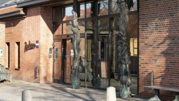 Comwell H.C. Andersens hotel hovedindgang set udefra. Foran hoveddøren ses en statue af HC Andersen, der sidder på en bænk.