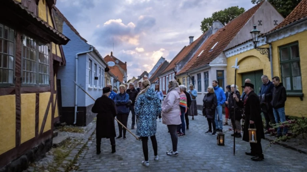 Vægter og cirka 20 personer på vægterture gennem Ærøskøbing i solnedgangen.