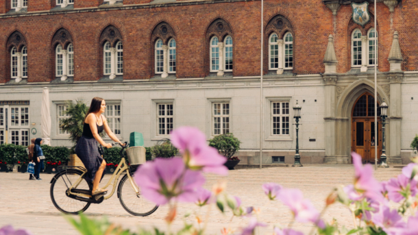 Cyklende kvinde foran bygning