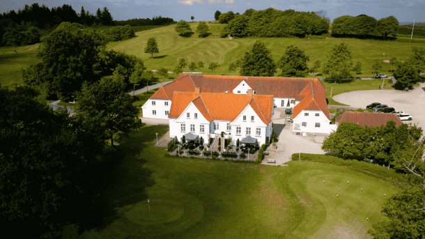 Hvid golfklub omkranset af træer og skov