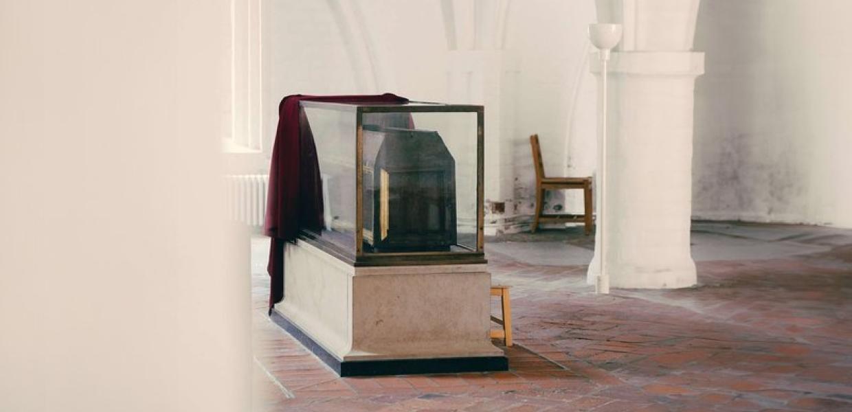 En gravsarkofag i en hvidmalet kirke med hvælvet loft 