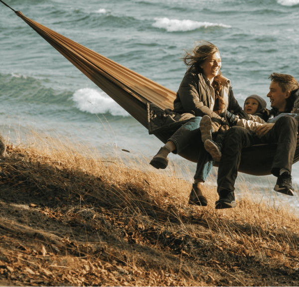 En familie på tre hygger i en hængekøje lige ud til havet på Fyn i Nyborg. 