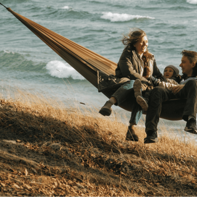 En familie på tre hygger i en hængekøje lige ud til havet på Fyn i Nyborg.