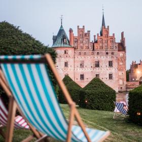 To af de klassiske stribede strand-liggestole i forgrunden - Egeskov Slot i baggrunden.