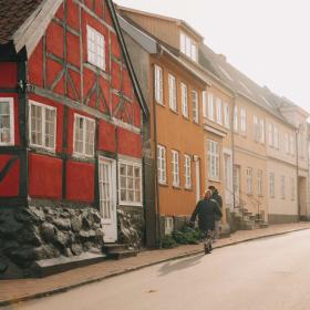 Farverige rækkehuse i gammel stil. En mand går på gaden forbi husene.